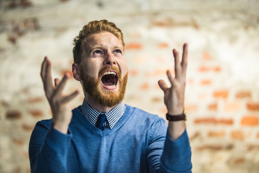 Young redhead businessman shouting from frustration.